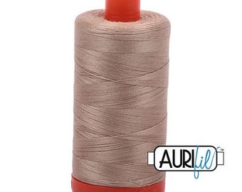 May include: A spool of Aurifil thread in a neutral taupe color. The thread is tightly wound around a cylindrical core with a bright orange top and base. The Aurifil logo is visible on the side.