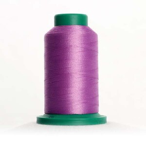 May include: A spool of purple thread with a green plastic top and bottom.