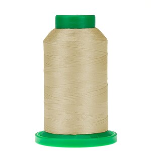 May include: A spool of beige thread with a green plastic top and bottom.