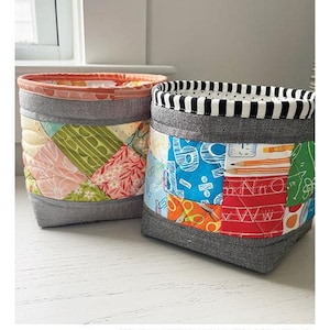 May include: Two handmade fabric baskets with patchwork designs. One basket has a black and white striped rim, the other has a floral rim. The baskets are approximately 5 inches by 6 inches by 4 inches. The text "Scrap Adventure Baskets" is at the top.