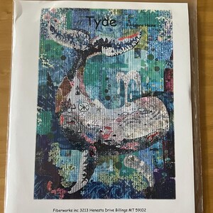 May include: A colorful art print titled "Tyde" featuring a whale with a detailed patchwork design. The whale is depicted in shades of blue, green, and white, with intricate patterns. The print is in a clear plastic sleeve.