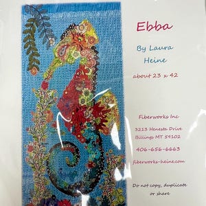 May include: A colorful seahorse art piece titled "Ebba" by Laura Heine. The seahorse is made of fabric with floral patterns in red, yellow, and green, against a blue background. The artwork is approximately 23 x 42 inches.