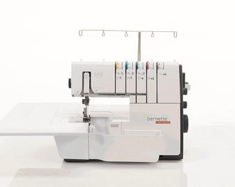 May include: A white Bernette b68 overlock sewing machine with a black accent. The machine has a fold-out table and a thread stand. The control panel has colored thread guides. The brand name is visible on the side.