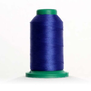 May include: A spool of dark blue thread with a green plastic top and bottom. The thread is wound tightly on the spool.
