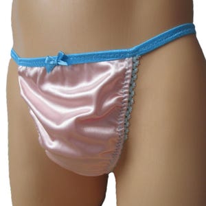 May include: A pair of light pink satin bikini-style underwear featuring a bright blue elastic waistband with a small matching blue bow at the center front and light blue scalloped lace trim along the side edges.