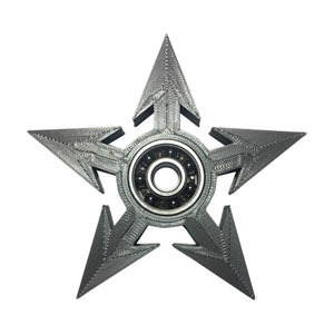 May include: A silver metal fidget spinner shaped like a five-pointed star with a bearing in the centre.