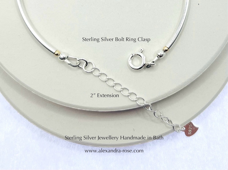 May include: A sterling silver necklace with a bolt ring clasp and a 2-inch extension. The necklace is silver with gold-colored accents. The text "Sterling Silver Bolt Ring Clasp", "2" Extension", and "Sterling Silver Jewellery Handmade in Bath" are visible.
