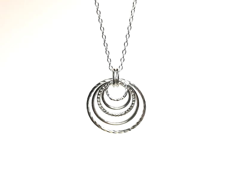 May include: A silver necklace with a pendant made of five interlocking circles.