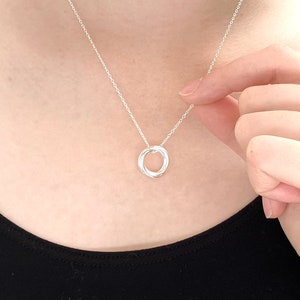 May include: A silver necklace with a simple, interlocking circle pendant.
