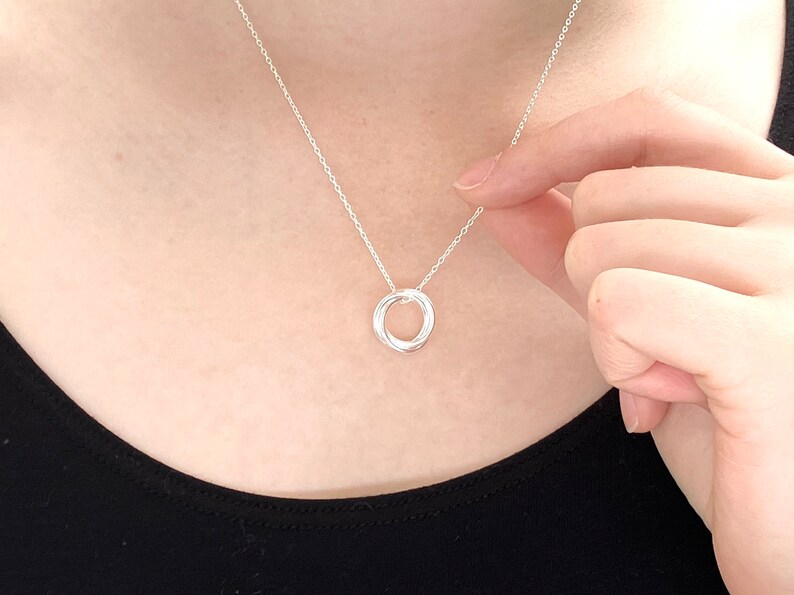 May include: A silver necklace with a simple, interlocking circle pendant.