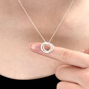 May include: A silver necklace with a pendant made of four interlocking circles.