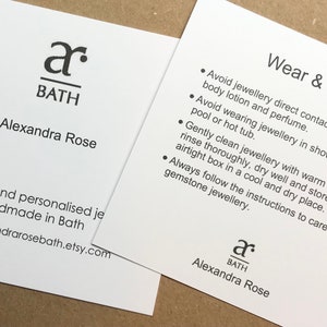 May include: White card with black text. The text reads "a BATH Alexandra Rose" and "Wear & Care" with a list of instructions for caring for jewelry. The card is a business card for a jewelry maker.