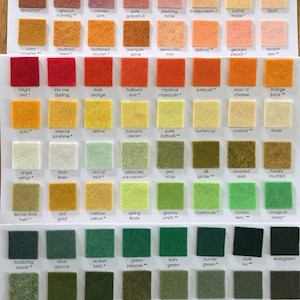 May include: A color chart featuring rows of small, square felt fabric swatches in various shades. Each swatch is labeled with a unique name, including colors like hot cocoa, bright red, and evergreen, arranged in a grid on a white background.