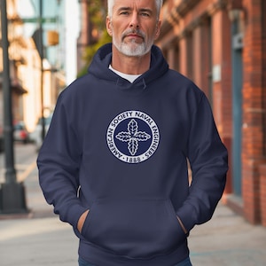 May include: A navy blue hooded sweatshirt featuring a white circular logo on the chest. The logo contains the text American Society of Naval Engineers 1888 surrounding a central oak leaf emblem. The hoodie has long sleeves and a front pouch pocket.