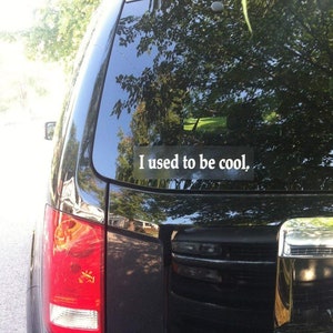 May include: A black car with a white sticker on the back window that says "I used to be cool."