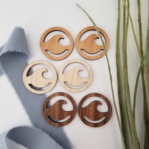 May include: Six wooden circles with a wave cutout design. Three circles are light brown and three circles are dark brown.
