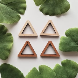 May include: Four unfinished wooden triangle earring blanks. Two are natural wood and two are stained a light brown color. Each triangle has a hole at the top for attaching earring findings.