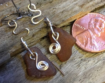 Pendientes de cristal de mar.  Marrón con bobinas de tono plateado en los alambres traseros de cierre de acero quirúrgico.