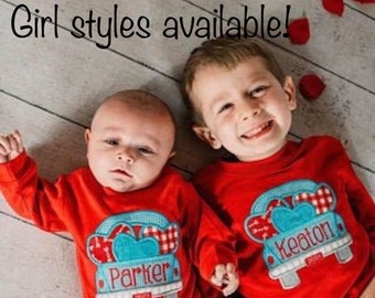 May include: Two children wearing red long-sleeved shirts with a blue truck design. The truck has hearts and a red and white checkered pattern. The shirts are personalized with the names "Parker" and "Keaton".