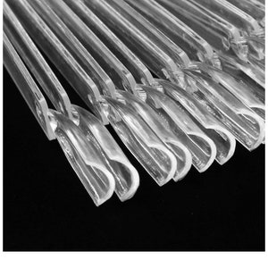 May include: A close-up of a stack of clear plastic hangers. The hangers are all the same size and shape, and they are arranged in a neat stack.