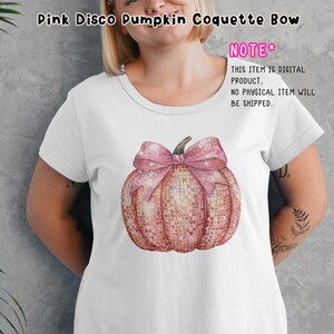 May include: A white t-shirt featuring a pink glitter pumpkin with a pink bow on top. The text "NOTE" is in pink with a star next to it. The text below says "THIS ITEM IS DIGITAL PRODUCT. NO PHYSICAL ITEM WILL BE SHIPPED."