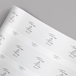 May include: White paper with repeating black text: "Tracey & Terry" and "30.01.21". The words "Wedding Day" are also printed on the paper. The paper is slightly angled, showing multiple instances of the text.