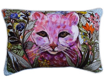 May include: A decorative pillow with a pink cat face surrounded by colorful flowers and leaves on a light blue background. The pillow has a white pom-pom trim.