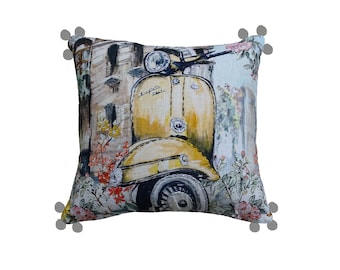 May include: A decorative throw pillow with a yellow Vespa scooter and floral design. The pillow has a light blue background and pom-poms on the corners.