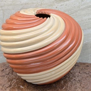 Puede incluir: Un cuenco de cerámica hecho a mano con un patrón de remolino de esmalte rojo y crema. El cuenco es redondo y tiene un acabado liso y brillante.