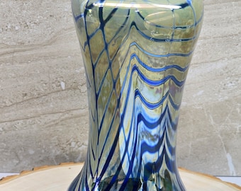 May include: A blue and gold glass vase with a wavy, abstract design. The vase has a wide mouth and a narrow base.