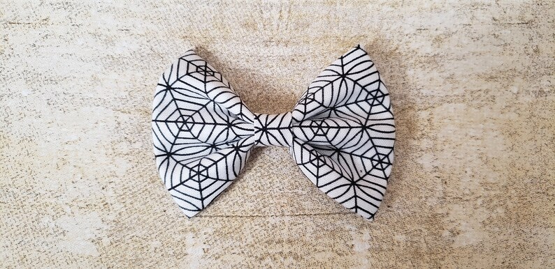 May include: A white bow with a black spiderweb pattern.