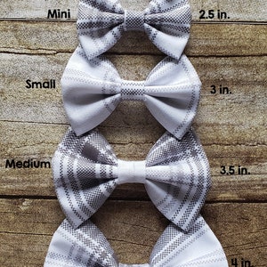 May include: Five plaid bow ties in different sizes, from itty-bitty to large, with measurements in inches. The bow ties are white with a gray plaid pattern.