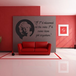 May include: A red sofa sits in a red and gray room with a black and white wall decal featuring a quote by Marilyn Monroe: "If I'd observed all the rules I'd never have got anywhere."