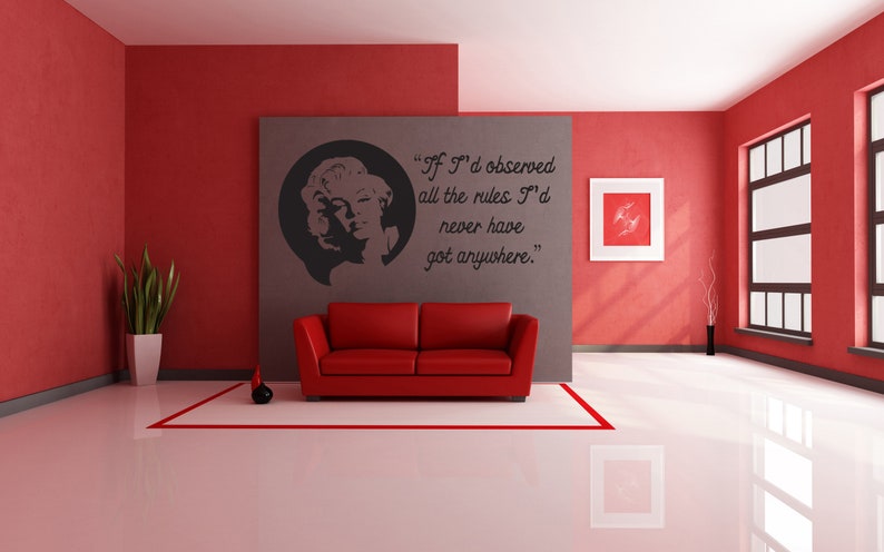 May include: A red sofa sits in a red and gray room with a black and white wall decal featuring a quote by Marilyn Monroe: "If I'd observed all the rules I'd never have got anywhere."