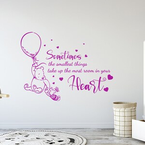 May include: Winnie the Pooh and Piglet holding a balloon with the quote "Sometimes the smallest things take up the most room in your heart." in purple lettering on a white wall.
