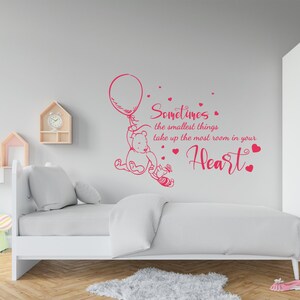May include: A pink Winnie the Pooh wall decal with a quote that reads "Sometimes the smallest things take up the most room in your heart." The decal features Winnie the Pooh holding a balloon and Piglet.
