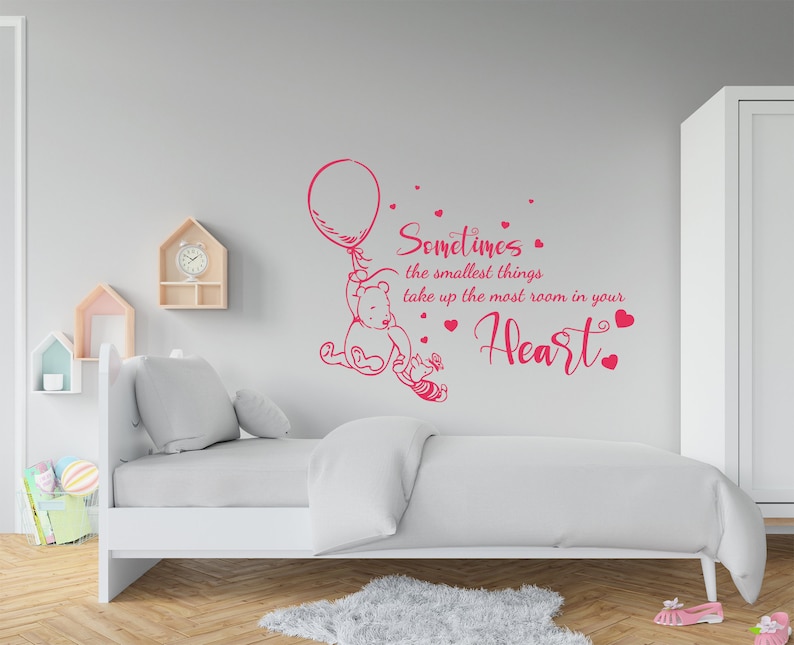 May include: A pink Winnie the Pooh wall decal with a quote that reads "Sometimes the smallest things take up the most room in your heart." The decal features Winnie the Pooh holding a balloon and Piglet.