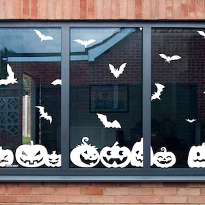Może przedstawiać: Okno ozdobione białymi wycięciami w kształcie halloweenowych motywów. Okno ma w dolnej części rząd uśmiechniętych dyni w kształcie jack-o'-lantern, a w górnej części latają nietoperze.
