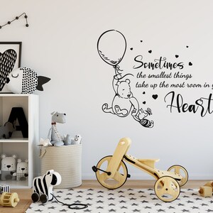 May include: Black and white Winnie the Pooh wall decal with a quote that reads "Sometimes the smallest things take up the most room in your heart." The decal features Winnie the Pooh holding a balloon and Piglet.