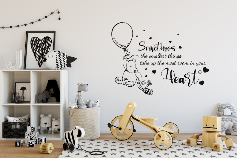 May include: Black and white Winnie the Pooh wall decal with a quote that reads "Sometimes the smallest things take up the most room in your heart." The decal features Winnie the Pooh holding a balloon and Piglet.