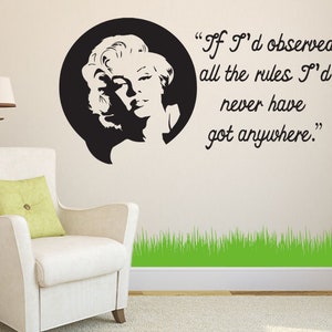 May include: Black and white silhouette of a woman with a quote that reads "If I'd observed all the rules I'd never have got anywhere." The quote is in a speech bubble above the woman's head. The background is a white wall with a green grass border at the bottom.
