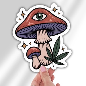 May include: A sticker featuring a whimsical mushroom design with a large eye on the cap. The mushroom is red and purple, with a light pink stem. A cannabis leaf and star accents complete the design.