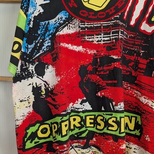 Pu&ograve; includere: T-shirt grafica vintage con colletto e maniche gialle. La maglietta presenta un design colorato con le parole "BODY GLOVE" e "OPPRESSIN" in un carattere audace in stile graffiti. Il design include elementi rossi, neri, bianchi, blu e verdi.