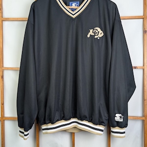 May include: Black long-sleeve pullover with a V-neck and gold, white, and black trim. The Colorado Buffaloes logo is on the chest. The Starter logo is on the sleeve.