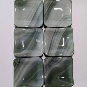 May include: Six small, square, green and white glass dishes with a swirled pattern. The dishes are arranged in two rows of three.