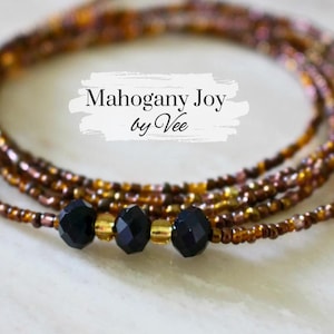 May include: A multi-strand beaded waist chain with black beads and gold accents. The chain is called "Mahogany Joy by Vee".