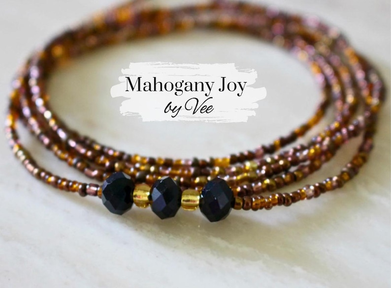 May include: A multi-strand beaded waist chain with black beads and gold accents. The chain is called "Mahogany Joy by Vee".