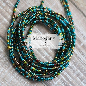 May include: A collection of colorful waist beads. The beads are a mix of teal, gold, brown, and green. The text "Mahogany Joy" is displayed on the image. The beads are arranged in a circular pattern.