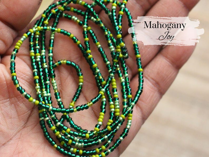 May include: A green and yellow beaded waist chain with the text "Mahogany Joy" on a white background.