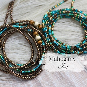 May include: A waist bead set with brown and turquoise beads. The beads are arranged in a layered pattern, with the brown beads forming the base and the turquoise beads layered on top. The beads are strung on a clear elastic cord. The waist beads are called "Mahogany Joy".